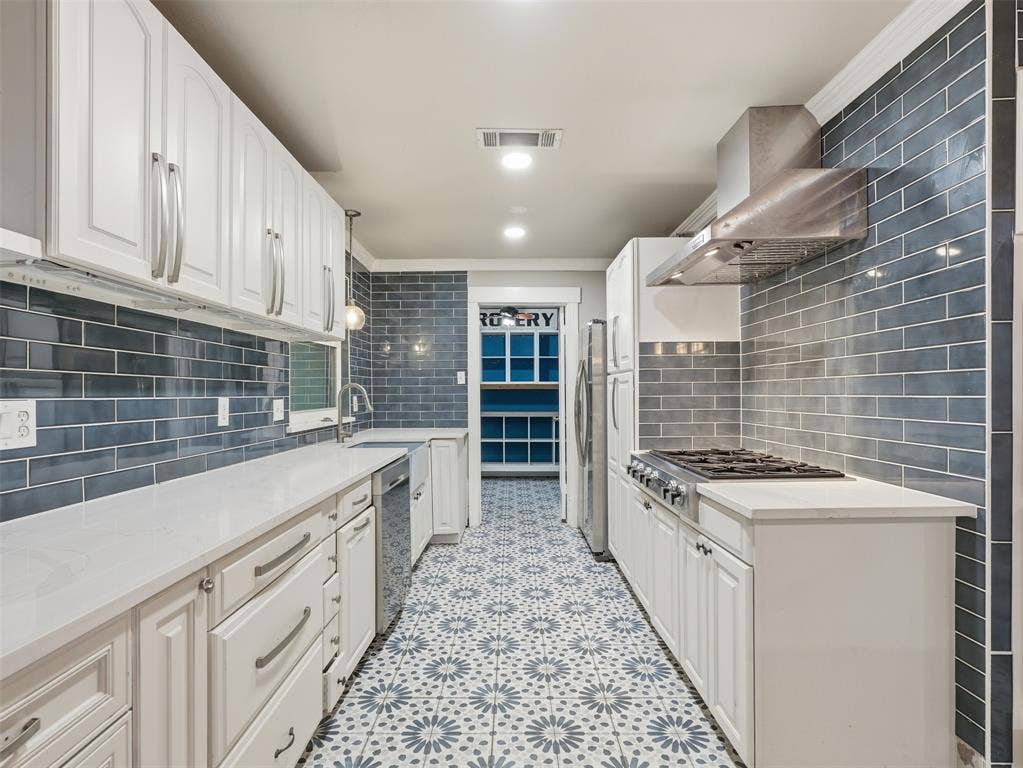 1402 Addington Street, Irving, TX 75062 White cabinetry, light countertops, subway tile backsplash, patterned tile flooring, and stainless steel appliances