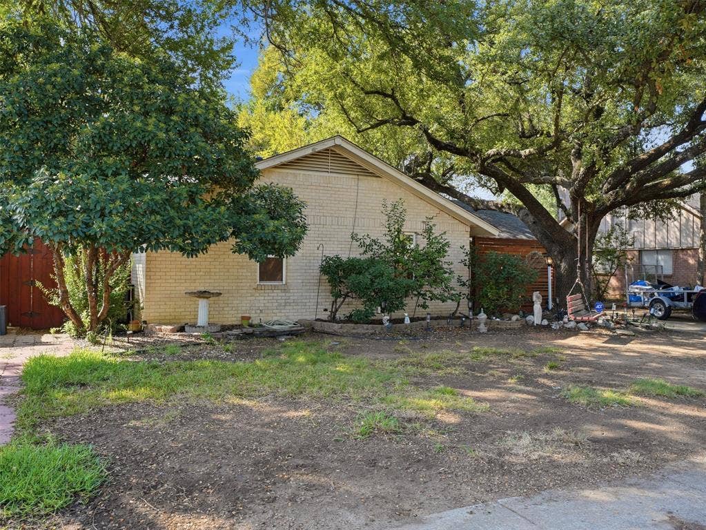 1402 Addington Street, Irving, TX 75062 Brick-clad exterior with a prominent mature tree, featuring a gabled roofline and surrounding landscaping