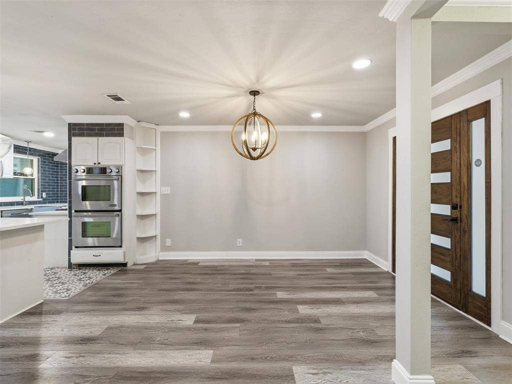 1402 Addington Street, Irving, TX 75062 Wood-finish flooring, recessed lighting, and a modern orb chandelier illuminate this open space