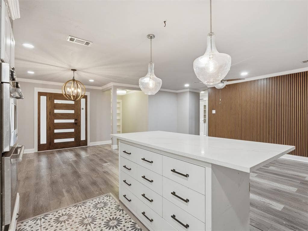 1402 Addington Street, Irving, TX 75062 Kitchen island with a white countertop and drawer storage, wood-finish flooring, and two clear glass pendant lights
