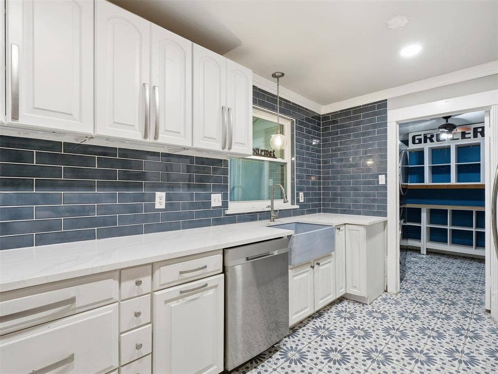 1402 Addington Street, Irving, TX 75062 White cabinetry, blue subway tile backsplash, white countertops, farmhouse sink, and patterned floor tiling