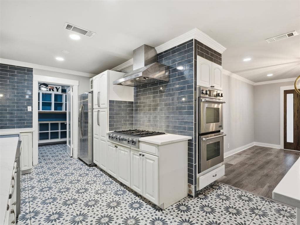 1402 Addington Street, Irving, TX 75062 Gourmet kitchen featuring stainless steel appliances, a gas range, double wall ovens, a tile backsplash, and patterned tile flooring