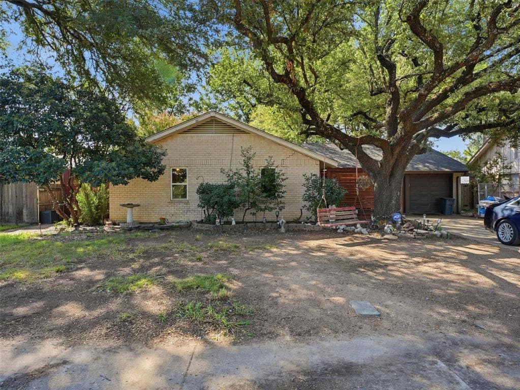 1402 Addington Street, Irving, TX 75062 Brick exterior with a prominent mature shade tree and attached garage