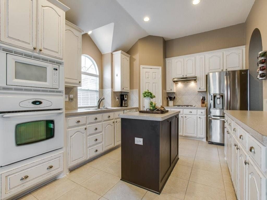 12316 Sailmaker Lane, Frisco, TX 75035 Kitchen featuring white cabinetry, a central island, stainless steel appliances, tile flooring, and vaulted ceilings