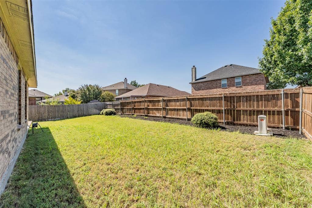 2205 Clairborne Drive, Fort Worth, TX 76177 Expansive backyard featuring a wood fence, established landscaping, and a brick exterior