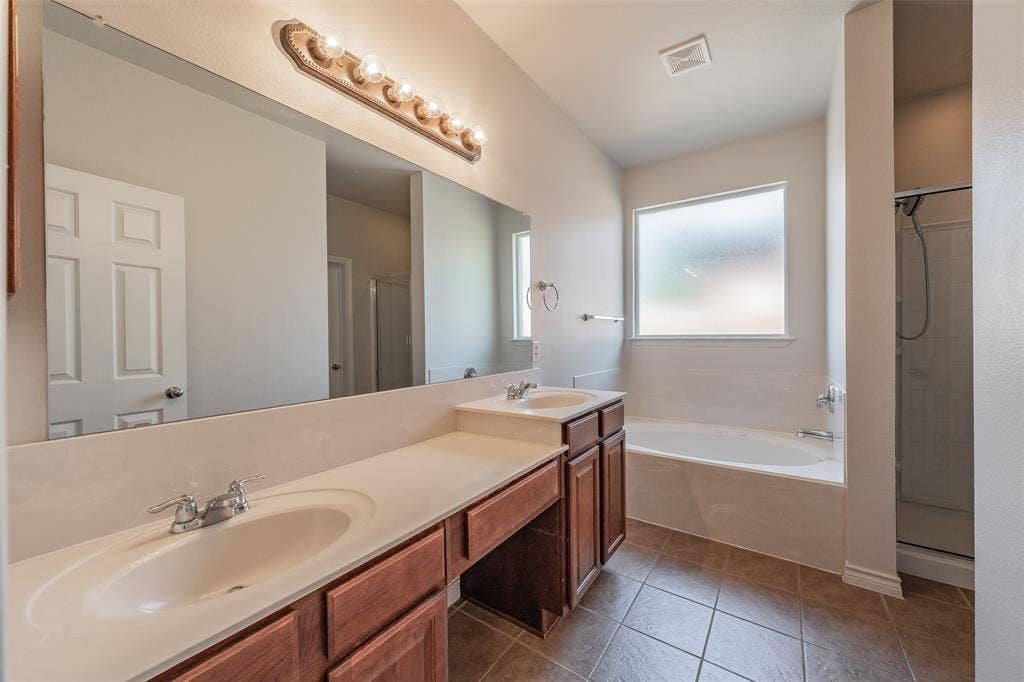 2205 Clairborne Drive, Fort Worth, TX 76177 Dual undermount sinks with chrome fixtures, wood-finish cabinetry, built-in bathtub, and a separate shower enclosure