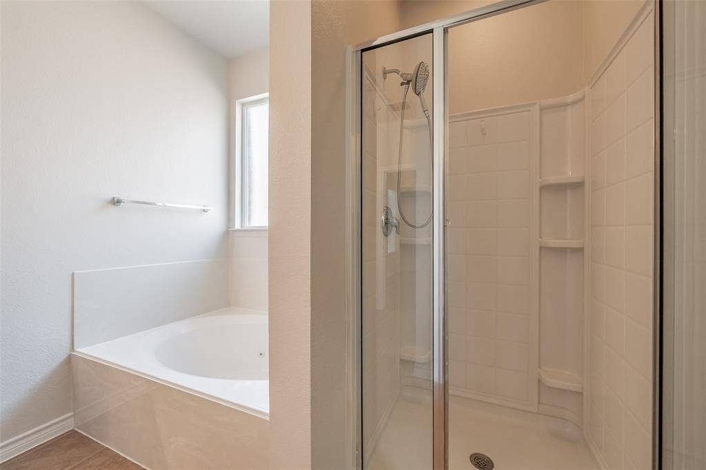 2205 Clairborne Drive, Fort Worth, TX 76177 Built-in bathtub with tiled surround, adjacent to a shower with a clear glass enclosure and integrated shelving