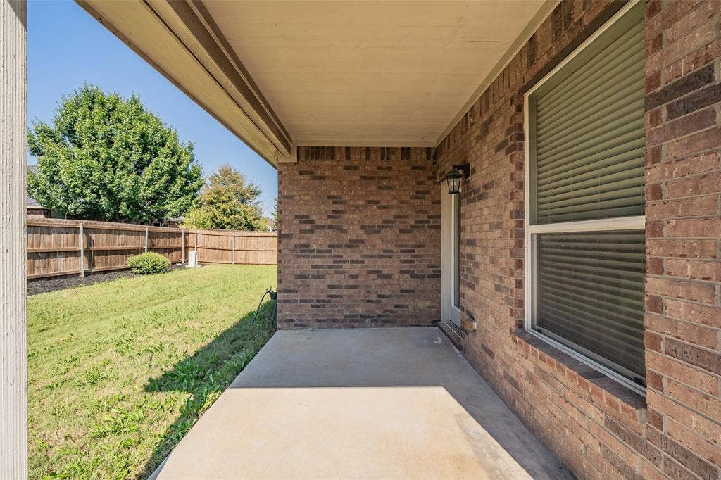 2205 Clairborne Drive, Fort Worth, TX 76177 Covered concrete patio with a brick exterior, outdoor wall sconce, and a fenced backyard
