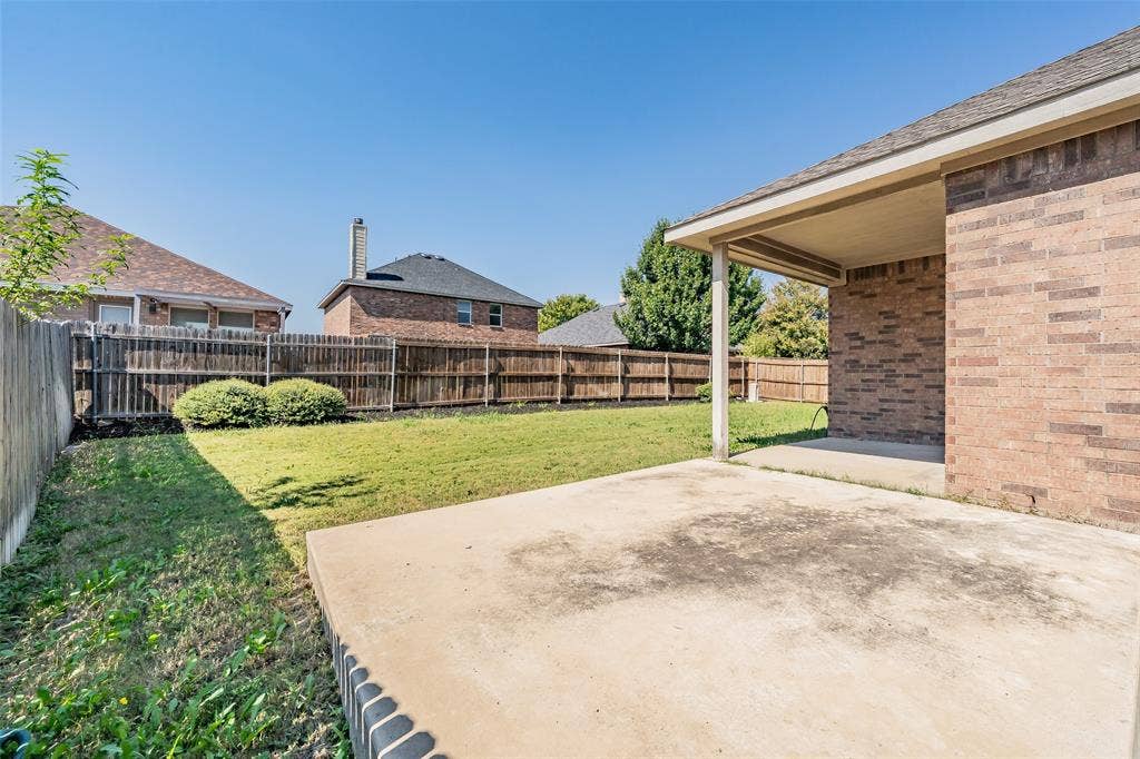 2205 Clairborne Drive, Fort Worth, TX 76177 Expansive grassy backyard featuring a wood fence, concrete patio, and covered porch area