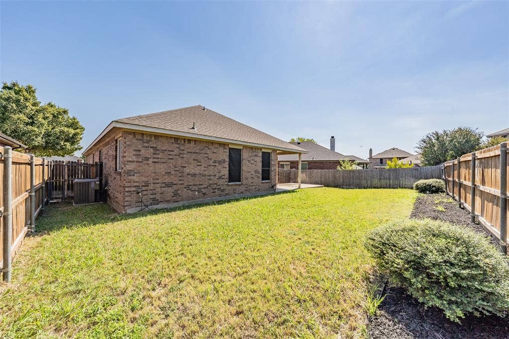 2205 Clairborne Drive, Fort Worth, TX 76177 Expansive backyard featuring a manicured lawn, brick exterior, covered patio, and wood privacy fencing
