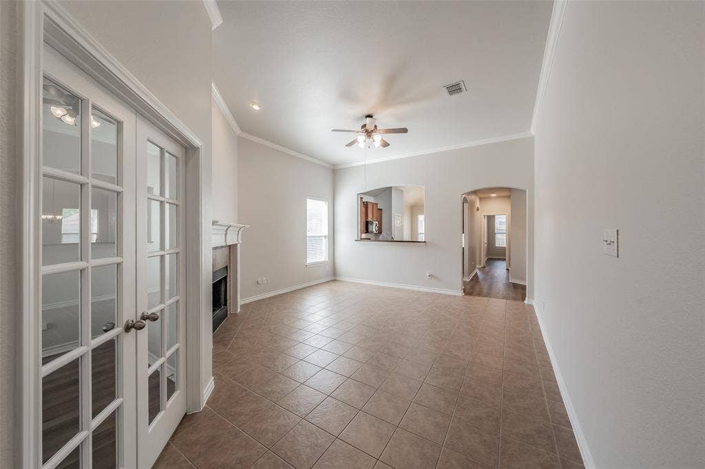 2205 Clairborne Drive, Fort Worth, TX 76177 Tile flooring, white French doors, fireplace with mantel, ceiling fan, and arched entryway