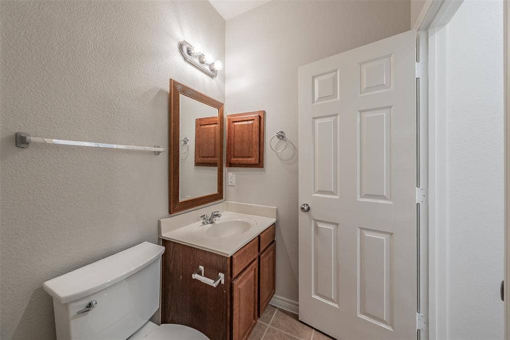 2205 Clairborne Drive, Fort Worth, TX 76177 Vanity with wood-finish cabinetry, integrated sink, and wall-mounted mirror