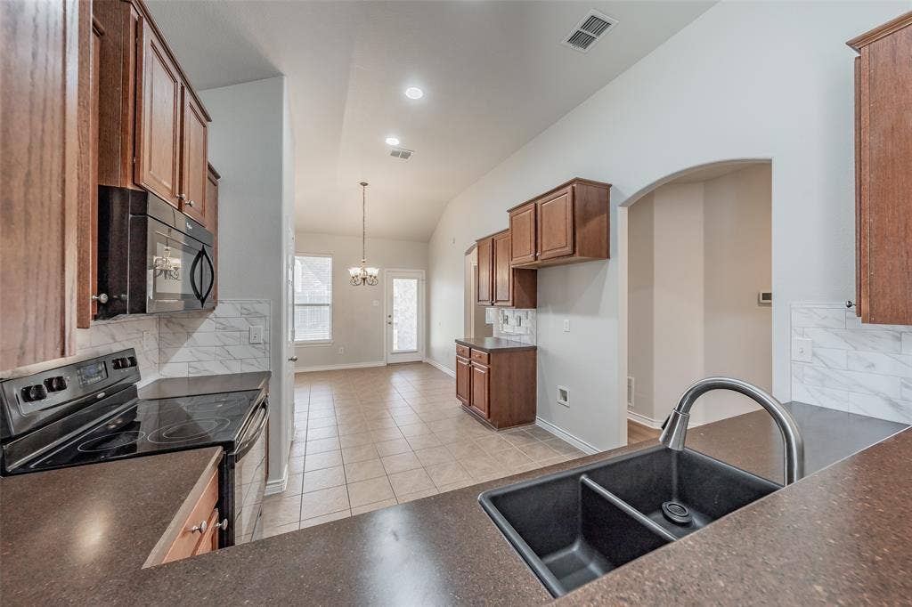 2205 Clairborne Drive, Fort Worth, TX 76177 Kitchen featuring wood-finish cabinetry, solid surface countertops, a dual basin sink, integrated appliances, and a tile backsplash