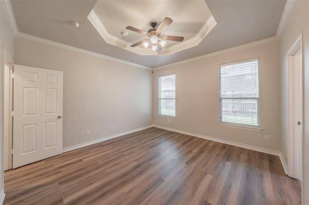 2205 Clairborne Drive, Fort Worth, TX 76177 Wood-finish flooring, tray ceiling with a ceiling fan, two windows with blinds, and a paneled door