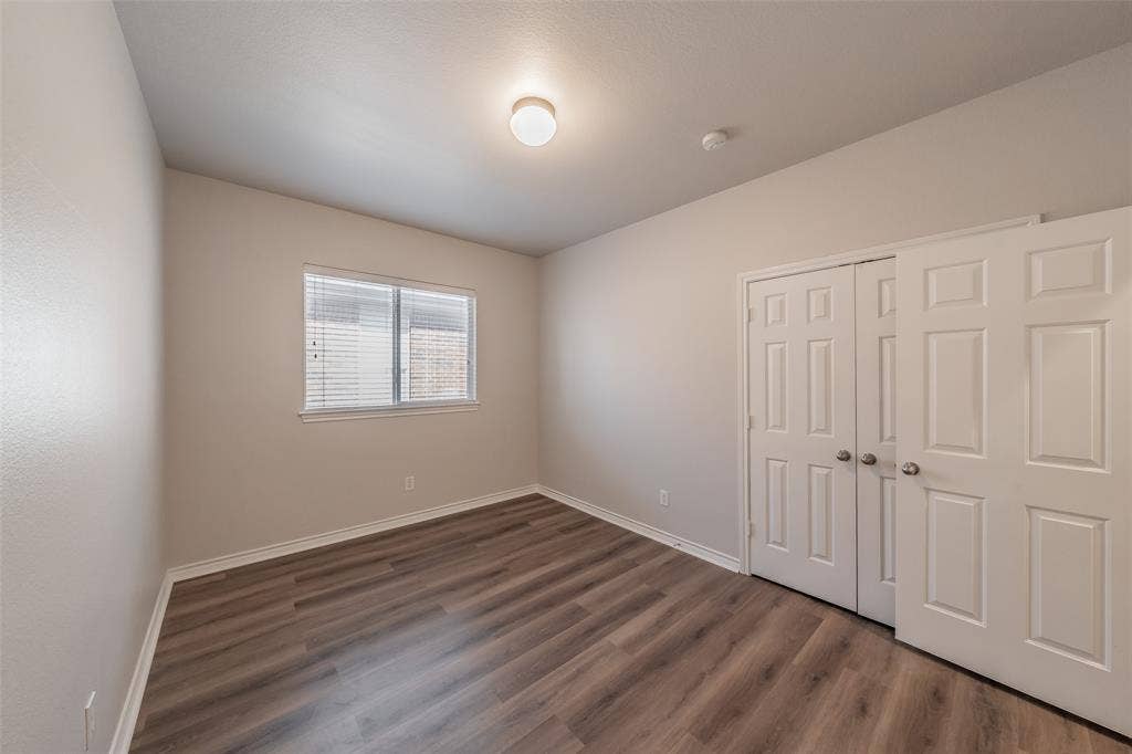 2205 Clairborne Drive, Fort Worth, TX 76177 Wood-finish flooring, white trim, window with blinds, and paneled bifold closet doors
