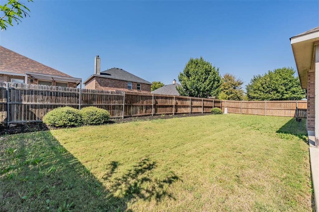 2205 Clairborne Drive, Fort Worth, TX 76177 Expansive yard featuring a wooden privacy fence, manicured lawn, and mature trees