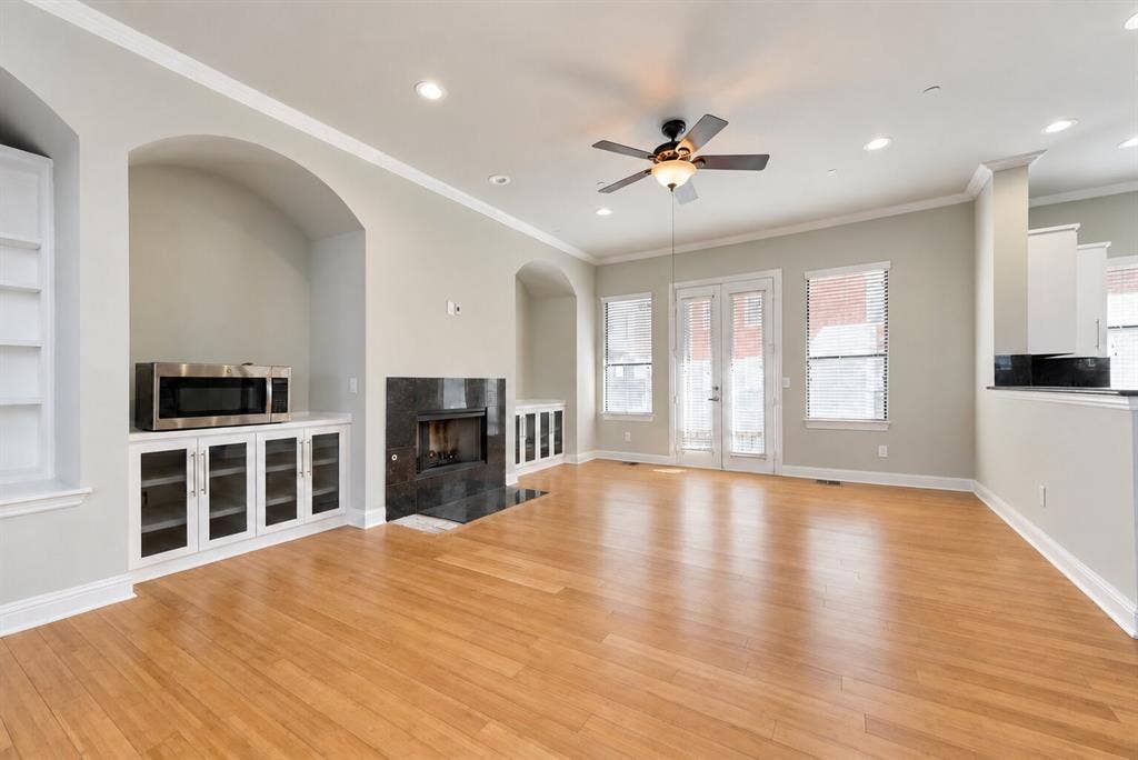 4432 Bowser Avenue, #C, Dallas, TX 75219 Hardwood-finish flooring, built-in shelving, fireplace with dark stone surround, recessed lighting, and ceiling fan