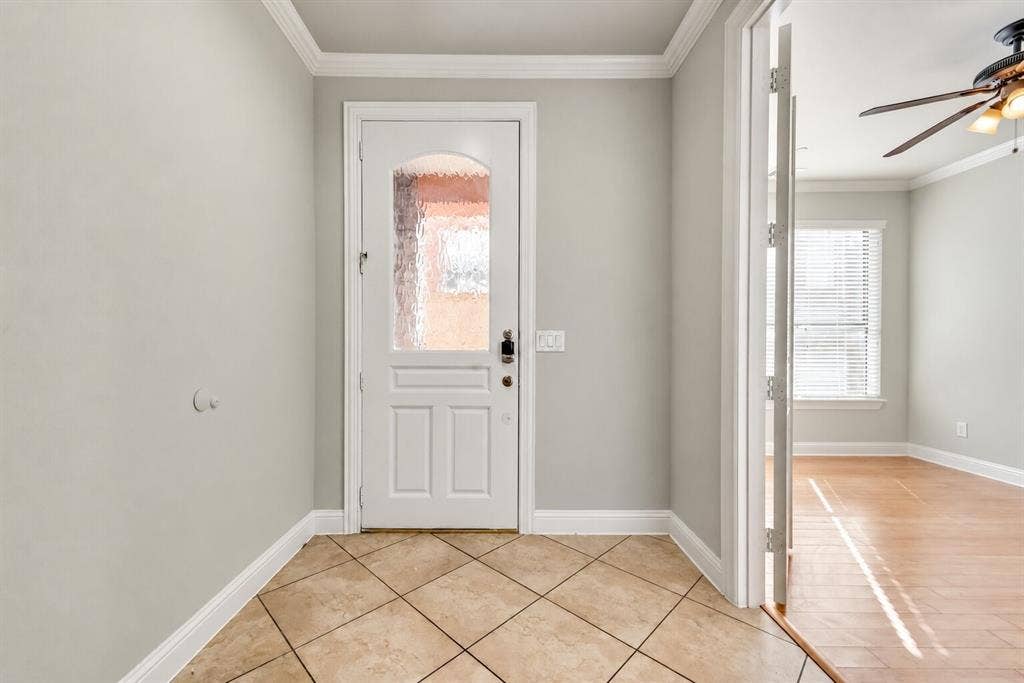 4432 Bowser Avenue, #C, Dallas, TX 75219 Entryway featuring ceramic tile flooring, a white paneled door with decorative glass, crown molding, and light-colored walls