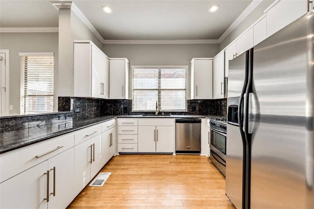 4432 Bowser Avenue, #C, Dallas, TX 75219 Modern kitchen featuring white cabinetry, dark stone countertops, stainless steel appliances, and wood-finish flooring