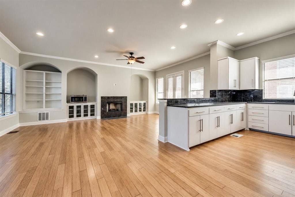 4432 Bowser Avenue, #C, Dallas, TX 75219 Hardwood flooring throughout, recessed lighting, built-in shelving, stone fireplace surround, and white cabinetry with dark countertops