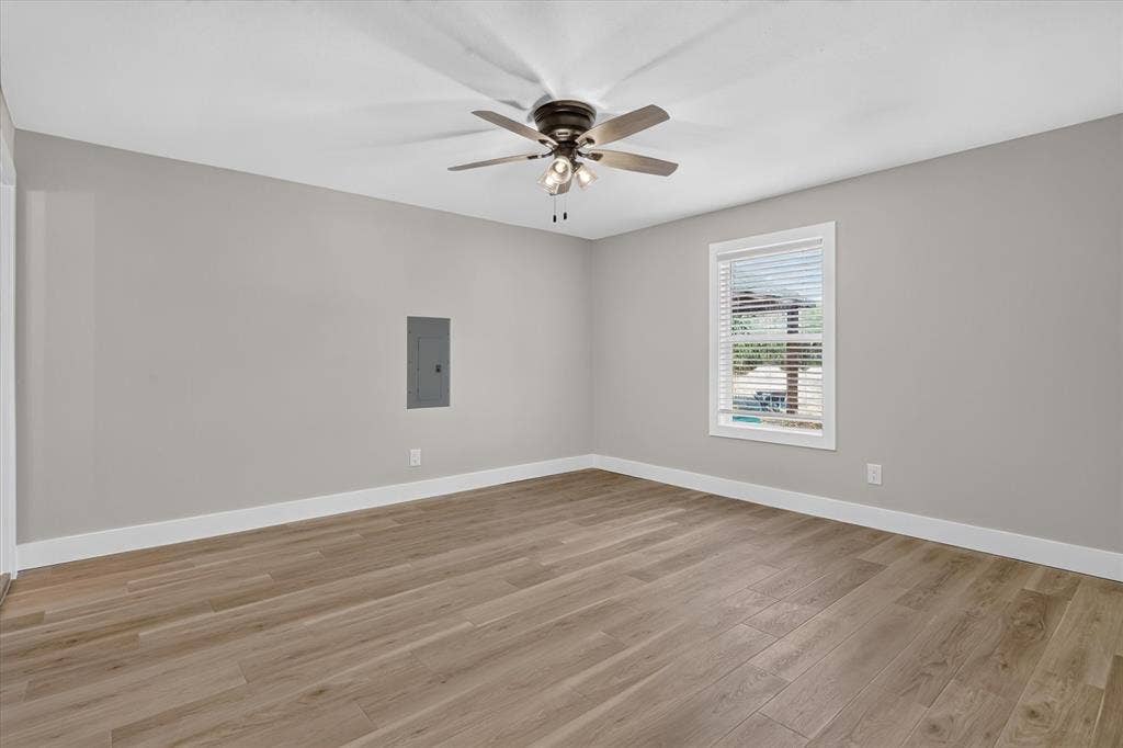 Neutral gray walls with white trim, wood-finish flooring, and a ceiling fan with integrated lighting