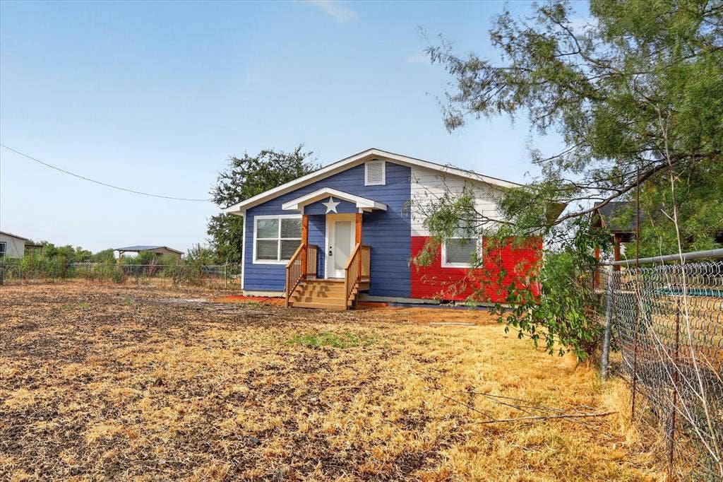 Vibrant exterior with blue and red siding, white trim, and a prominent front porch with wood railings