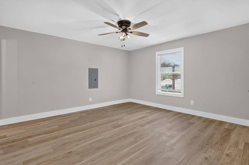 Wood-finish flooring, neutral wall tones, white trim, window with blinds, and a ceiling fan with integrated lighting