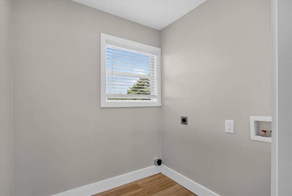Light-toned painted walls with a white framed window, wood-finish flooring, and white trim