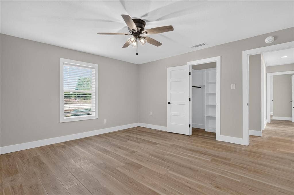 Wood-finish flooring, white trim, and a ceiling fan with light fixture