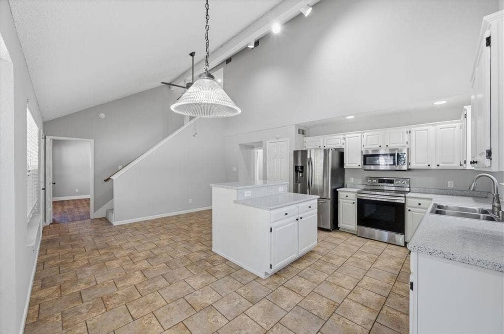 5016 Mill Creek Trail, Fort Worth, TX 76179 Vaulted ceiling with track lighting, white cabinetry, stainless steel appliances, speckled countertops, and tile flooring