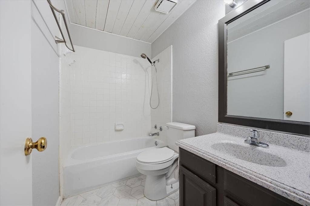 5016 Mill Creek Trail, Fort Worth, TX 76179 Modern bathroom featuring a white subway tile surround with integrated shower-tub combination, dual vanity with stone-finish countertop and undermount sink, framed mirror with chrome hardware, and ceramic tile flooring