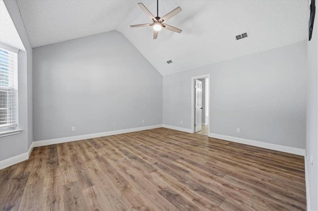 5016 Mill Creek Trail, Fort Worth, TX 76179 Spacious primary bedroom featuring vaulted ceilings, wood-finish flooring throughout, and abundant natural light from large windows