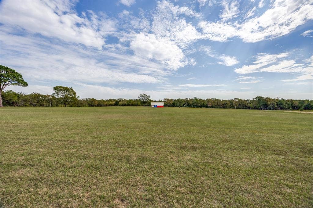 Expansive green field with a distant red and white structure