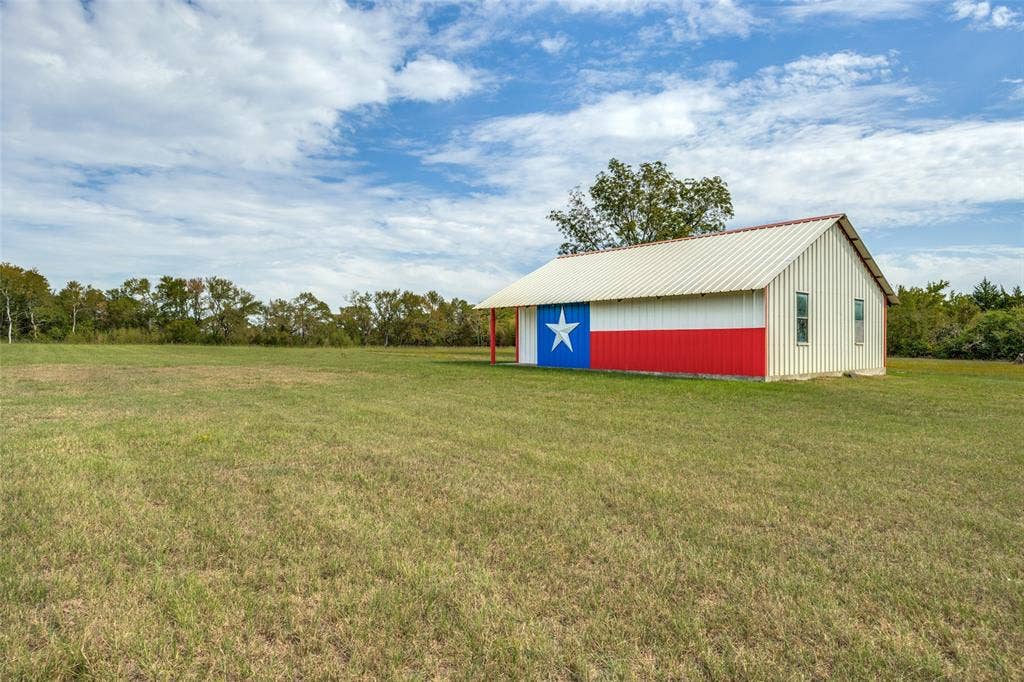 Barn structure featuring a metal roof, vertical siding, and an exterior painted with a flag design