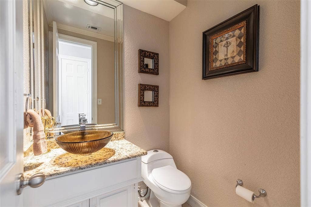 A glass vessel sink, granite countertop and beveled mirror add character to the separate powder bath.