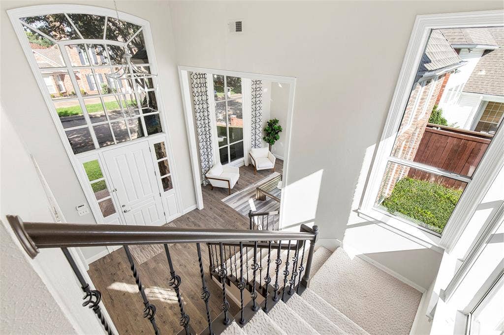 Upstairs landing overlooks the two-story entry, where expansive windows fill the staircase and foyer with natural light.
