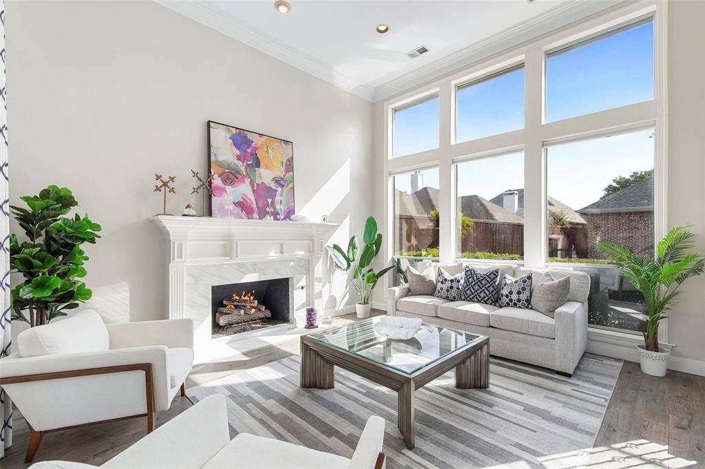 Tall windows bring abundant natural light into the front living room, where a fireplace anchors a comfortable space for conversation.