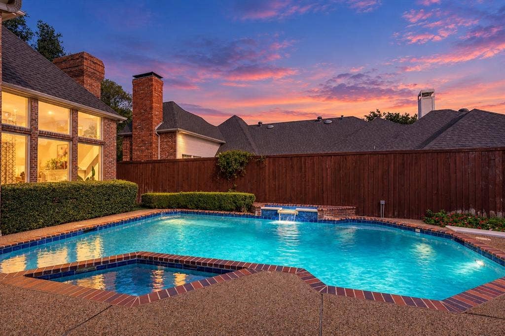 Your private backyard oasis takes on a whole new feel at twilight. The illuminated pool and attached spa shimmer beneath the evening sky, while the waterfall adds a relaxing backdrop. Settle into a shaded seat on the covered patio and let a quick evening outside turn into your favorite part of the day.