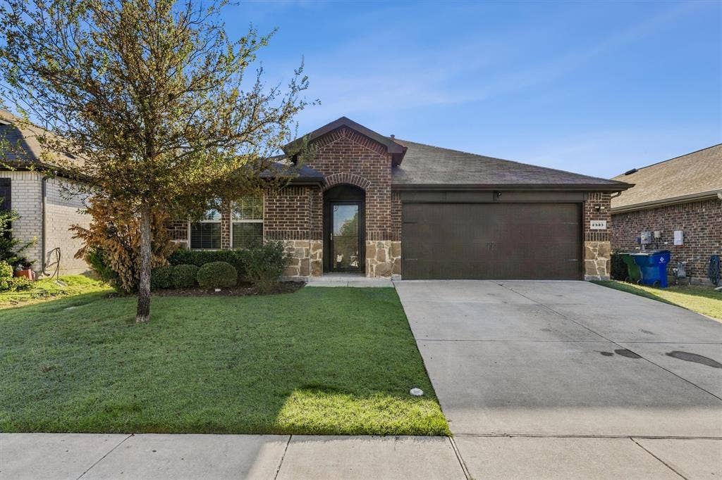2333 Bellewood Court, Crandall, TX 75114 Brick facade with stone accents, arched entry, attached garage, concrete driveway, and front lawn with mature landscaping
