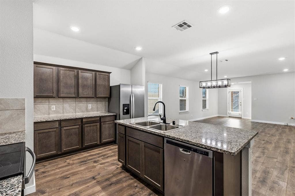 2333 Bellewood Court, Crandall, TX 75114 Kitchen featuring wood-finish flooring, dark wood cabinetry, granite countertops, and stainless steel appliances