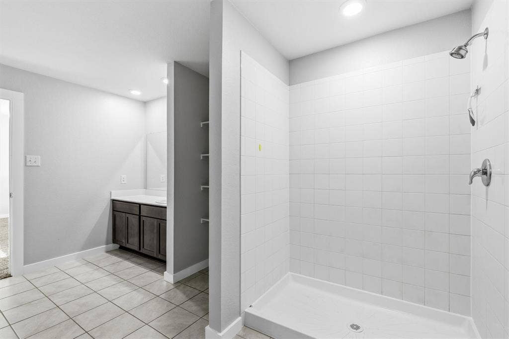 2333 Bellewood Court, Crandall, TX 75114 Tiled flooring, built-in shelving, vanity with storage, white countertop, and a tiled shower