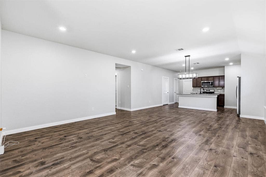 2333 Bellewood Court, Crandall, TX 75114 Wood-finish flooring throughout, recessed lighting, and a kitchen featuring dark wood cabinetry, stainless steel appliances, and an island with a breakfast bar