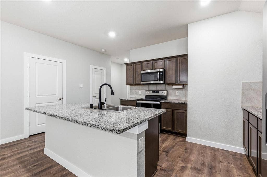 2333 Bellewood Court, Crandall, TX 75114 Kitchen with a central island featuring a double-basin sink and a black gooseneck faucet