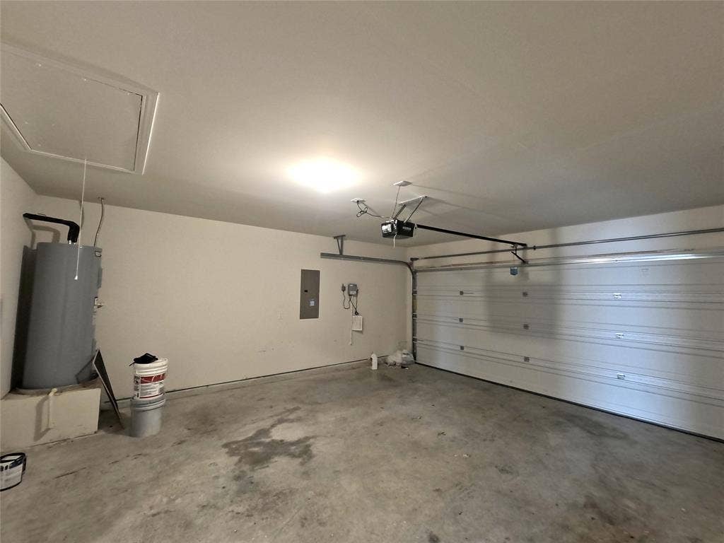 1148 Samantha Drive, Dallas, TX 75253 Garage with a roll-up door, exposed automatic garage door opener, and a water heater