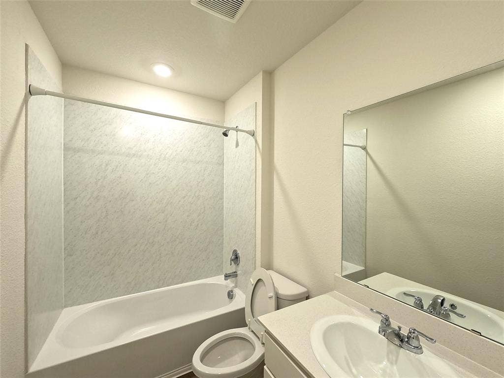 1148 Samantha Drive, Dallas, TX 75253 Built-in bathtub with shower, white vanity sink with chrome fixtures, and an integrated wall mirror