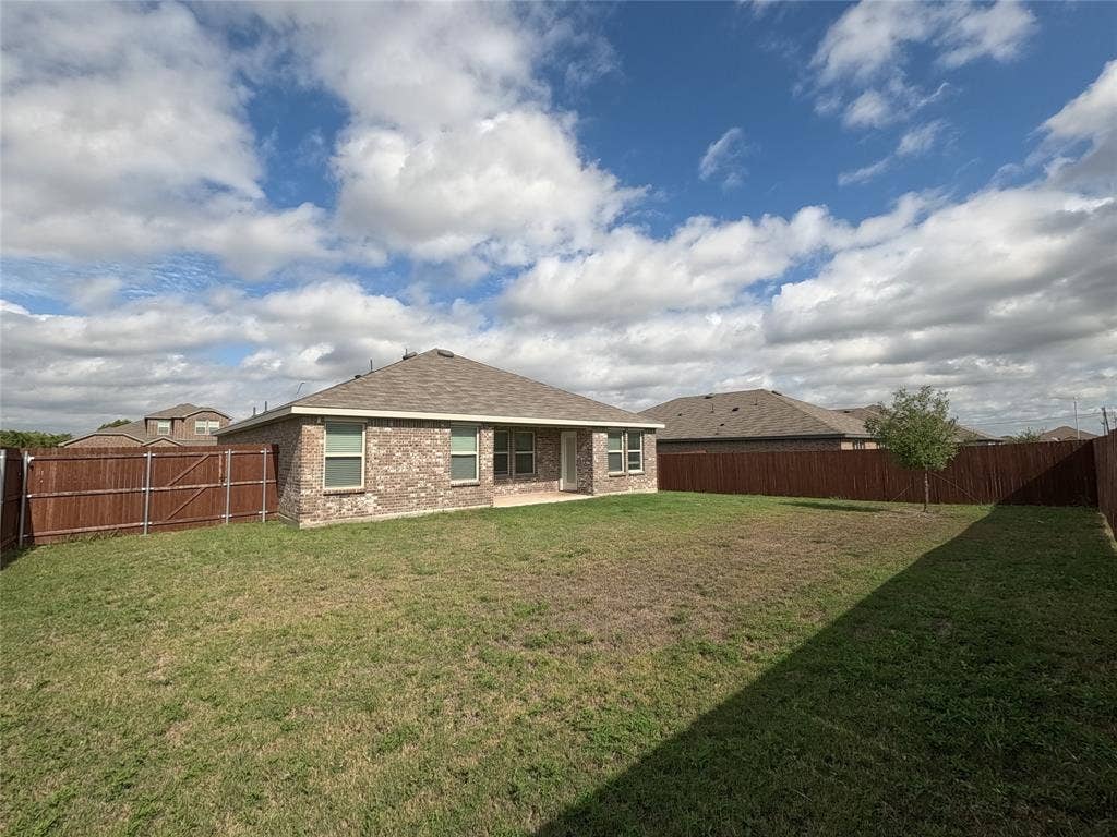 1148 Samantha Drive, Dallas, TX 75253 Expansive backyard featuring a manicured lawn, complete wood fencing, and a brick exterior home with a shingle roof
