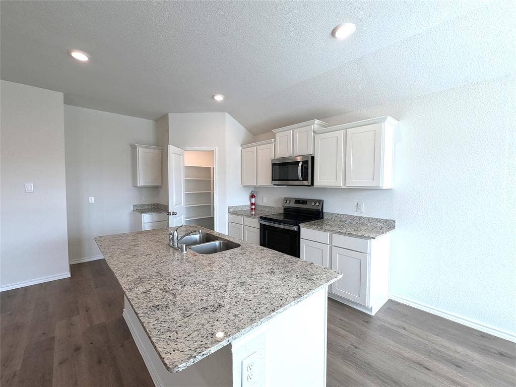 1148 Samantha Drive, Dallas, TX 75253 Kitchen featuring an island with dual basin sink, stainless steel appliances, granite countertops, white cabinetry, and wood-finish flooring