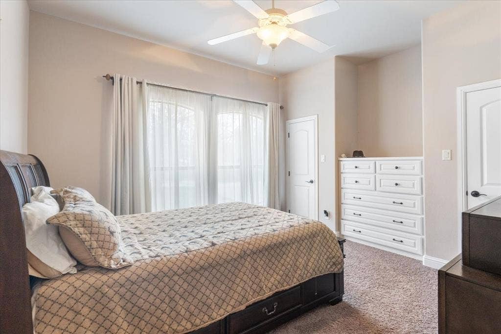 117 Redtail Court, Weatherford, TX 76088 Carpeted room featuring a ceiling fan with integrated lighting, built-in dresser with multiple drawers, and arched patio doors