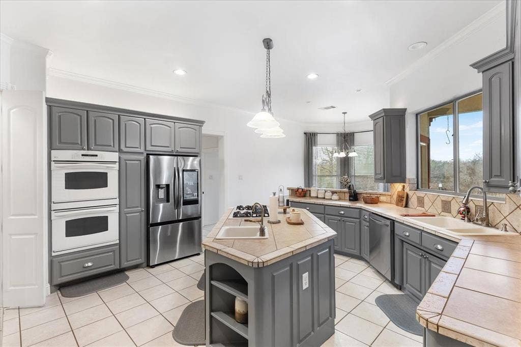 117 Redtail Court, Weatherford, TX 76088 Kitchen featuring gray cabinetry, tile flooring, built-in double ovens, stainless steel refrigerator, and an island with a gas cooktop