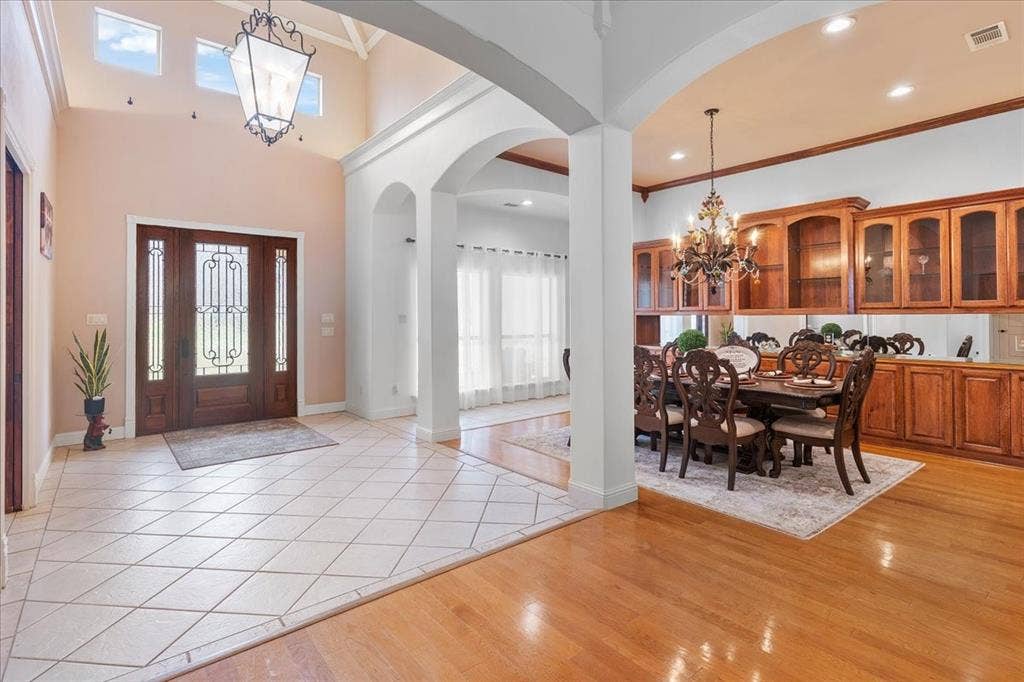 117 Redtail Court, Weatherford, TX 76088 Foyer featuring high ceilings, natural wood-finish flooring, diamond-patterned tile, arched architectural detailing, and a decorative lantern-style chandelier